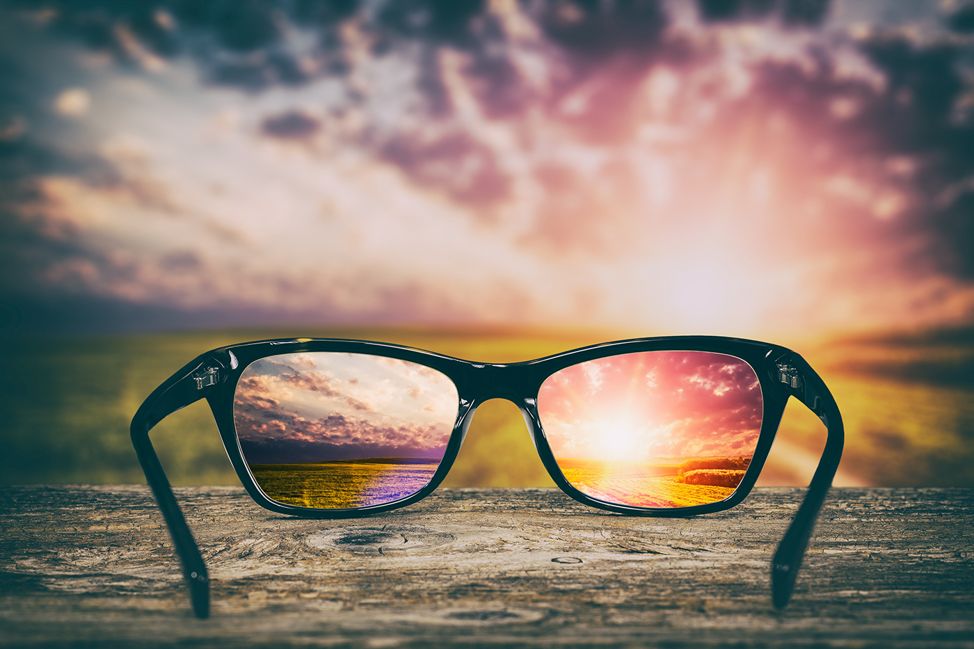 An out-of-focus view of a sunrise, with a focused version in the lenses of a pair of spectacles.