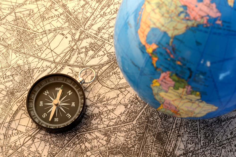 A globe and compass overlaid on an antique map